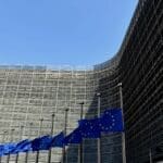 European Union flags displayed outside a modern EU institution building.