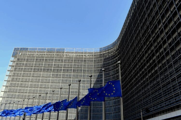 European Union flags displayed outside a modern EU institution building.