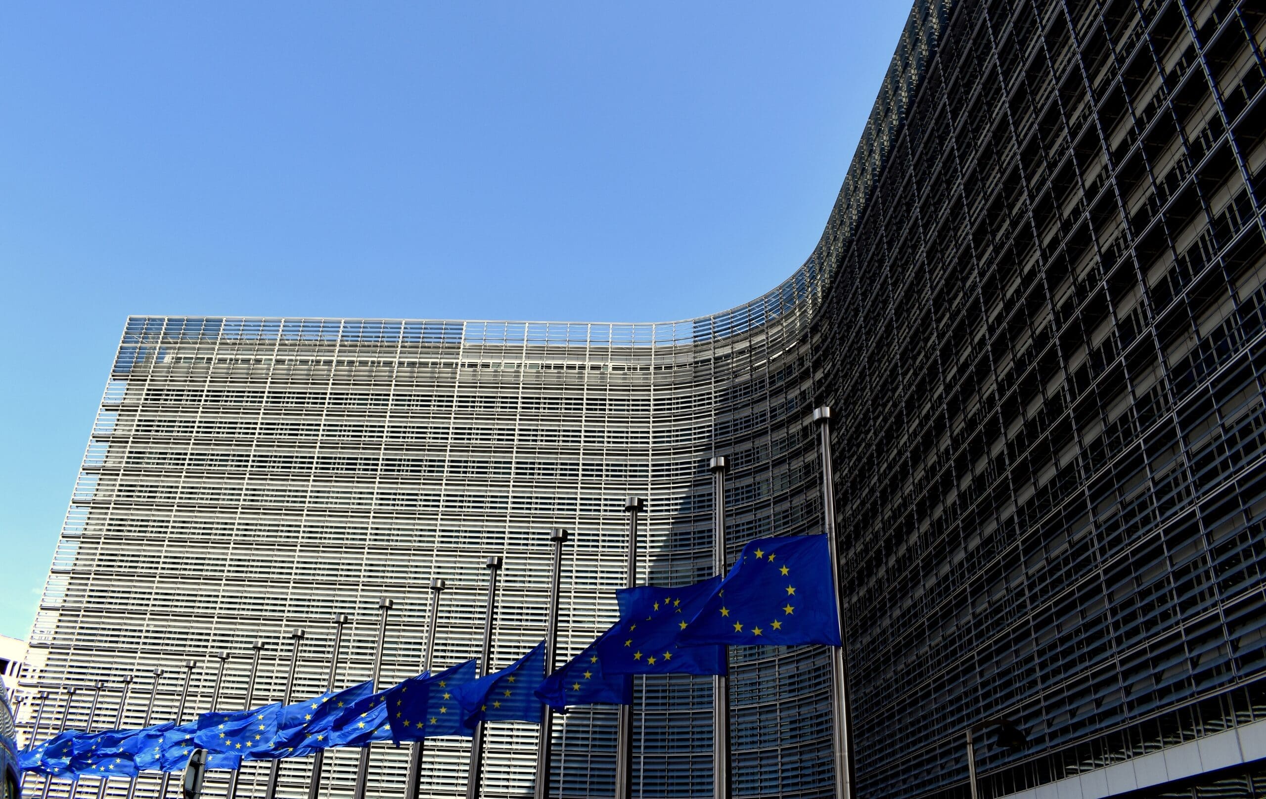 European Union flags displayed outside a modern EU institution building.