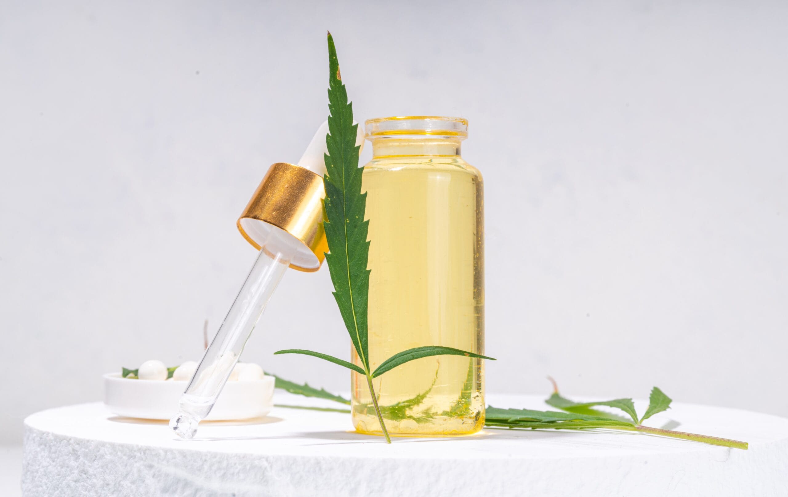CBD oil cosmetic ingredient in a dropper bottle with cannabis leaf.