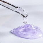 Close-up of a cosmetic serum being dispensed from a dropper onto a gel formulation.