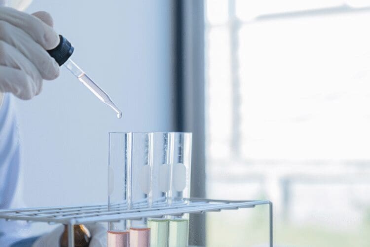 Laboratory technician using a pipette to test samples in test tubes.