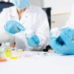 Laboratory professionals evaluating cosmetic packaging and product samples during quality testing.