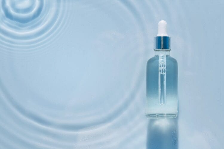 Hydrating facial serum in a dropper bottle displayed on a blue background with water ripples.