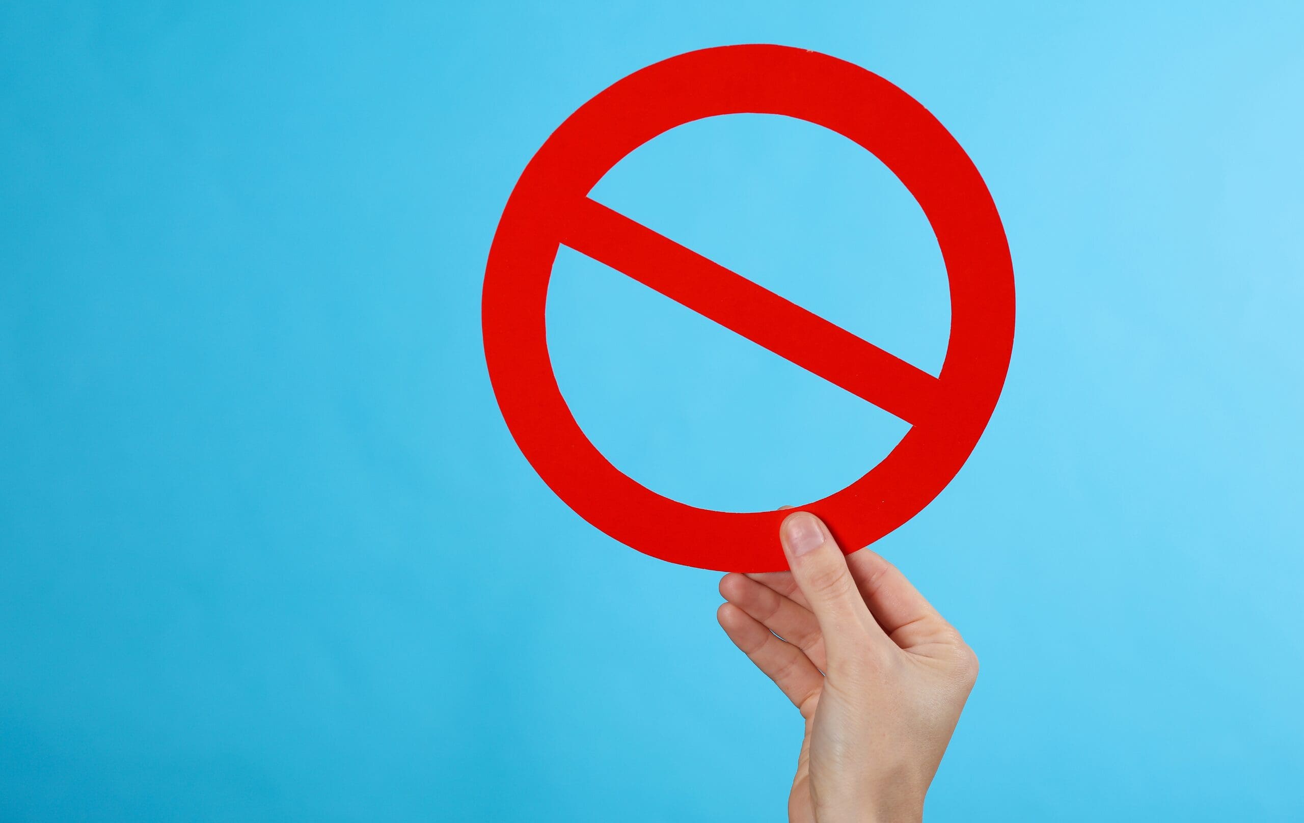 Hand holding a prohibition sign representing restricted substances and regulatory compliance requirements.
