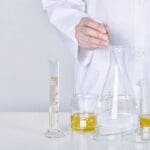 Scientist preparing a cosmetic formulation in a laboratory using laboratory glassware and testing equipment.