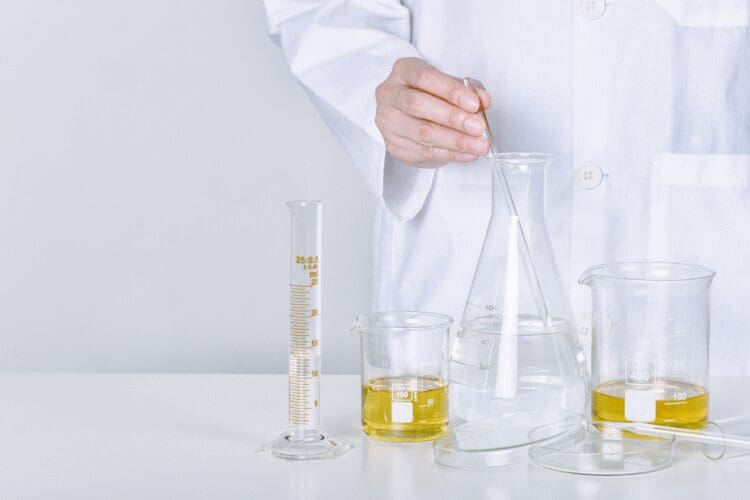 Scientist preparing a cosmetic formulation in a laboratory using laboratory glassware and testing equipment.