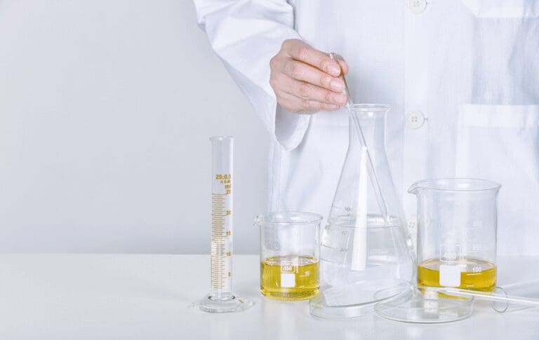 Scientist preparing a cosmetic formulation in a laboratory using laboratory glassware and testing equipment.