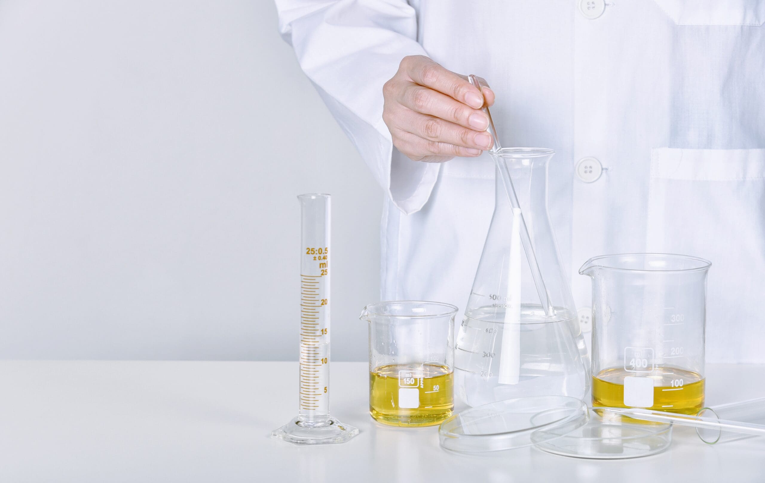 Scientist preparing a cosmetic formulation in a laboratory using laboratory glassware and testing equipment.