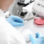 Scientist performing laboratory testing on a cosmetic cream formulation using scientific equipment.