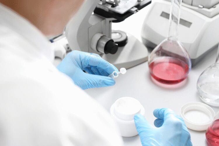 Scientist performing laboratory testing on a cosmetic cream formulation using scientific equipment.