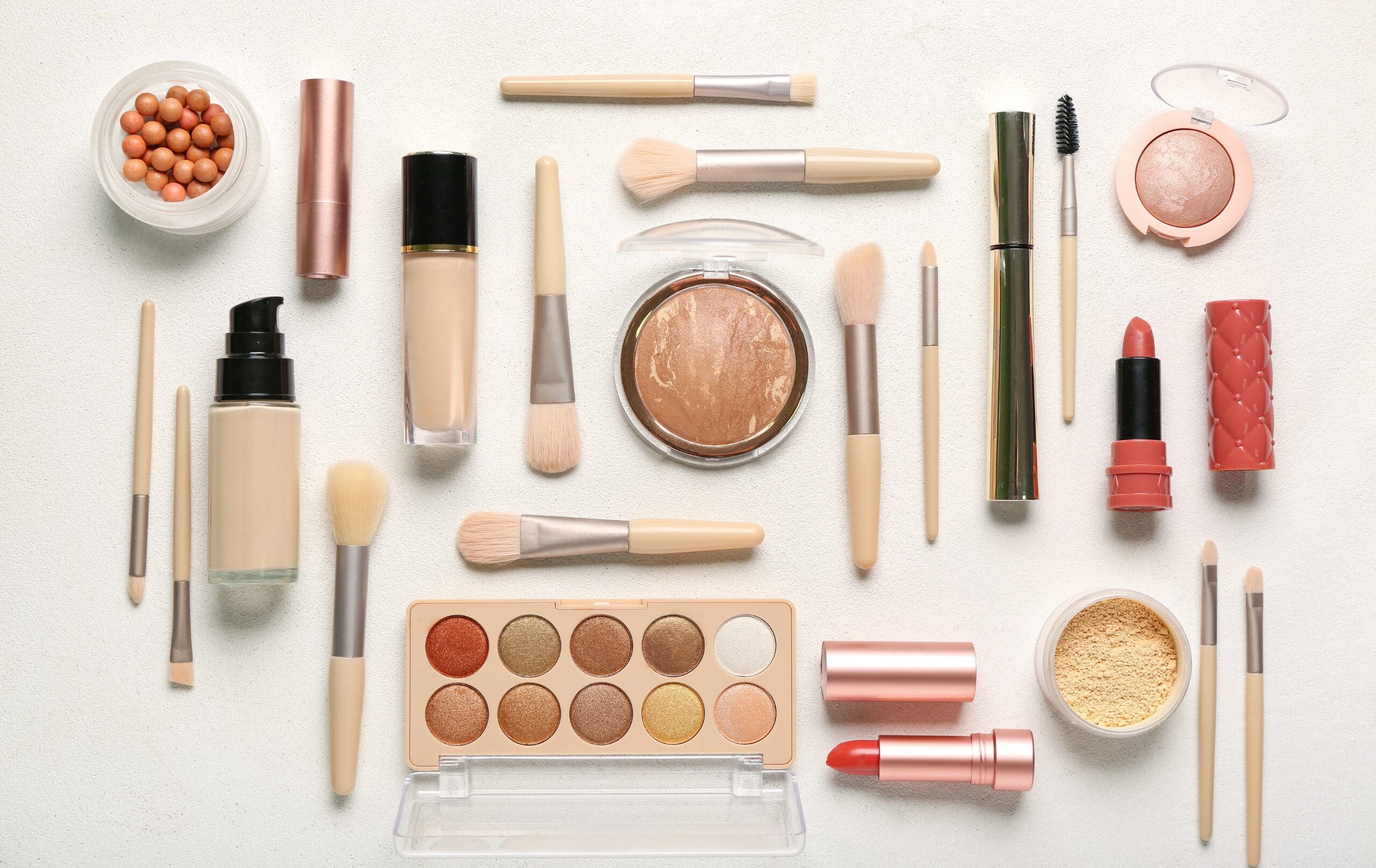 Selection of makeup and cosmetic products including lipstick, foundation, eyeshadow and powders.