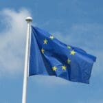European Union flag waving against a cloudy blue sky representing EU regulations and compliance.