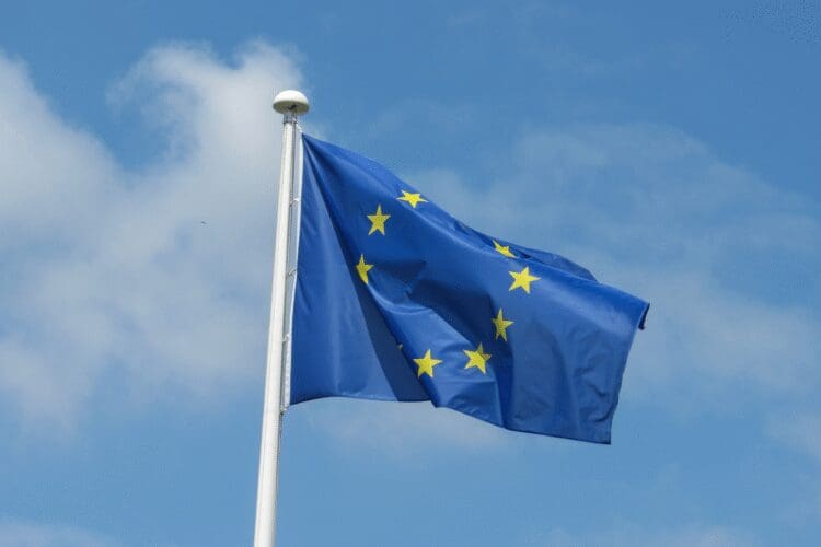European Union flag waving against a cloudy blue sky representing EU regulations and compliance.