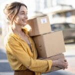 Woman carrying cardboard delivery boxes outside