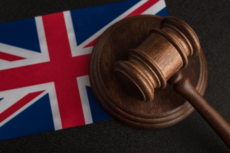 Wooden judge's gavel placed on a United Kingdom flag, representing UK regulations, legislation, and legal compliance.