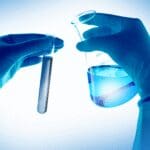 Laboratory professional holding a test tube and beaker during product testing.