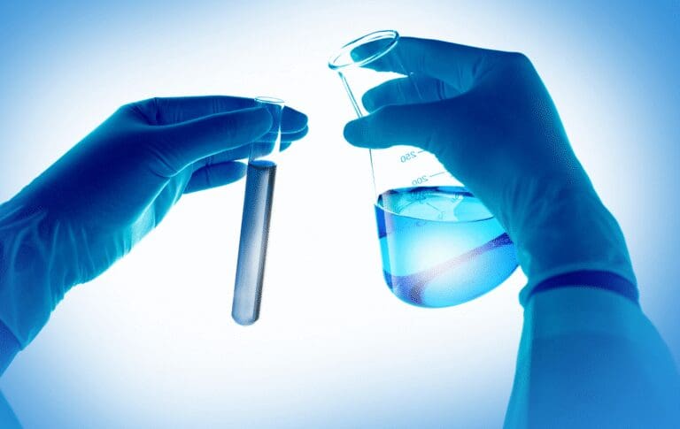 Laboratory professional holding a test tube and beaker during product testing.