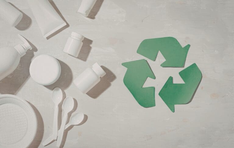 Recycling symbol surrounded by plastic packaging and disposable plastic products.
